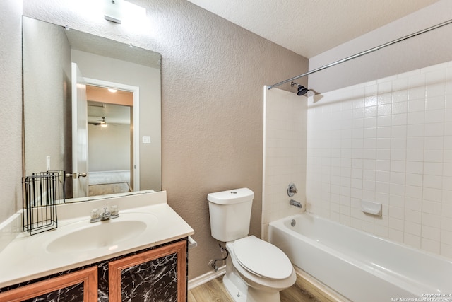 full bathroom featuring vanity, wood-type flooring, tiled shower / bath combo, toilet, and a textured ceiling