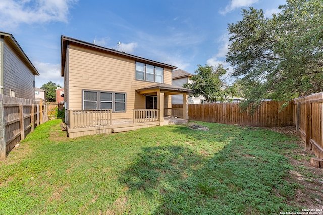 back of property with a yard and a wooden deck