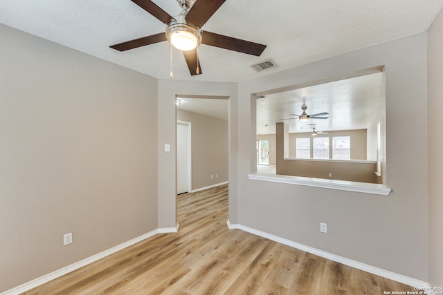 spare room with ceiling fan, light hardwood / wood-style floors, and a textured ceiling