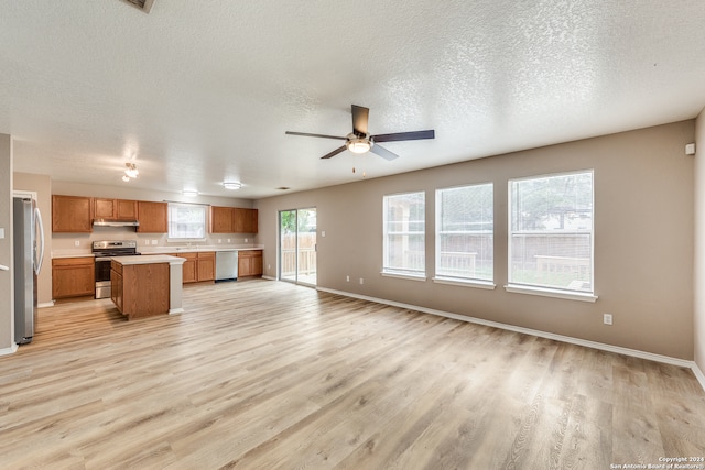 kitchen with a kitchen island, ceiling fan, light hardwood / wood-style floors, appliances with stainless steel finishes, and a textured ceiling