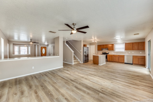 kitchen with a center island, sink, light hardwood / wood-style floors, appliances with stainless steel finishes, and a textured ceiling