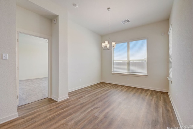 unfurnished room with wood-type flooring and a notable chandelier