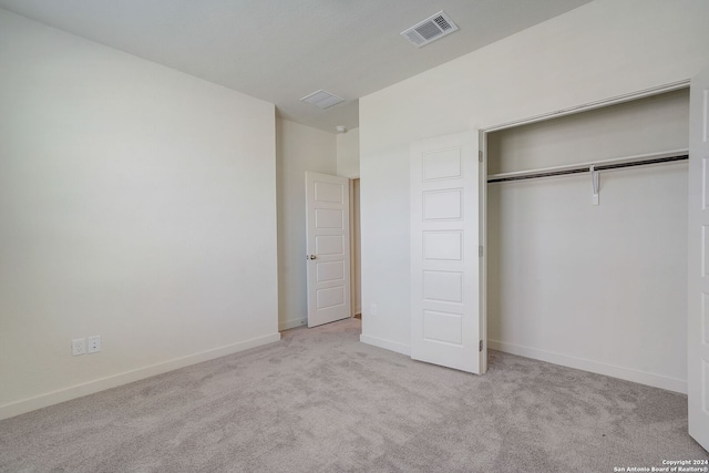 unfurnished bedroom with light carpet and a closet