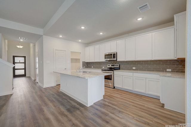 kitchen with light stone counters, stainless steel appliances, white cabinets, sink, and light hardwood / wood-style floors