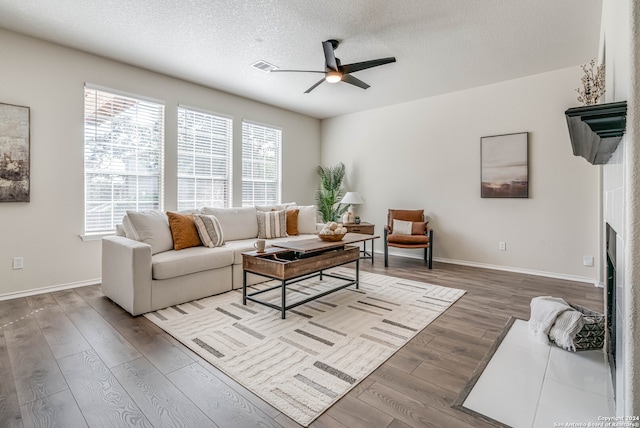 living room featuring ceiling fan, wood-type flooring, and a textured ceiling