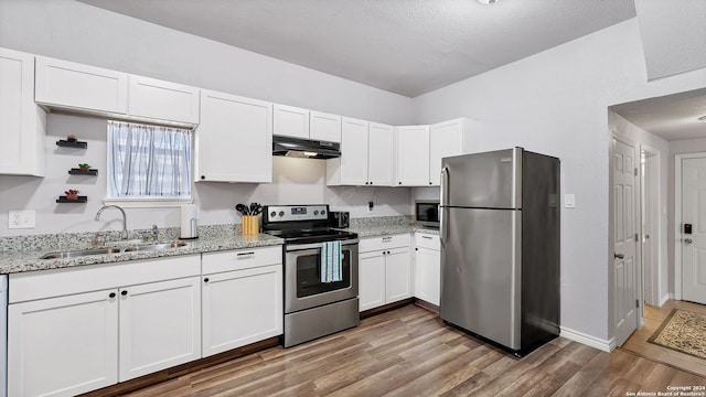 kitchen featuring sink, white cabinetry, hardwood / wood-style flooring, appliances with stainless steel finishes, and light stone countertops