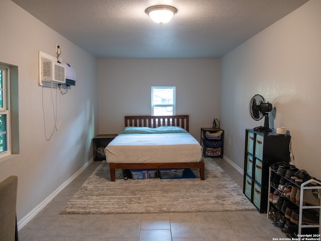 tiled bedroom featuring a textured ceiling and an AC wall unit