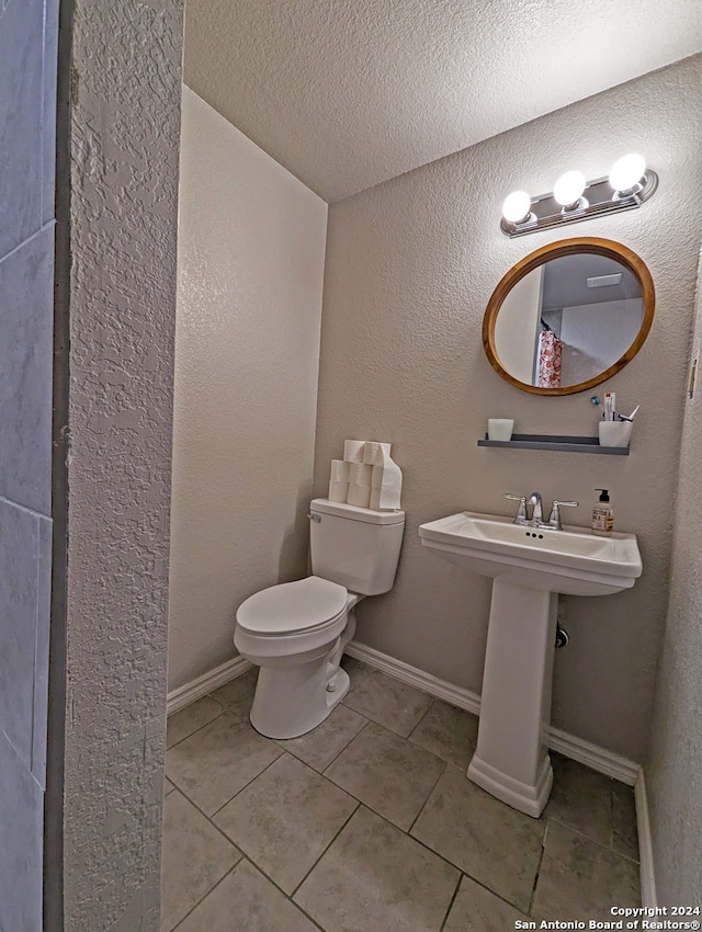 bathroom with a textured ceiling, tile patterned flooring, and toilet