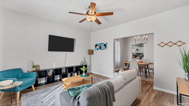 living room with ceiling fan with notable chandelier and light wood-type flooring