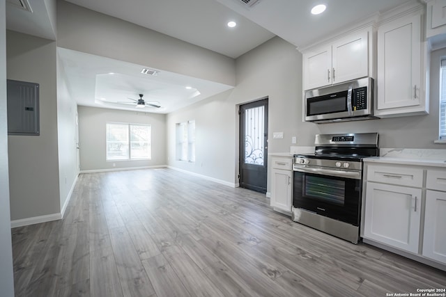 kitchen with light wood-type flooring, ceiling fan, stainless steel appliances, white cabinets, and electric panel