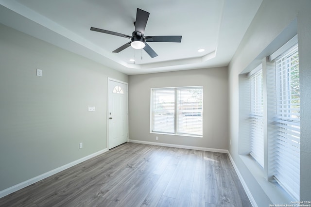 unfurnished room featuring ceiling fan, a tray ceiling, and wood-type flooring