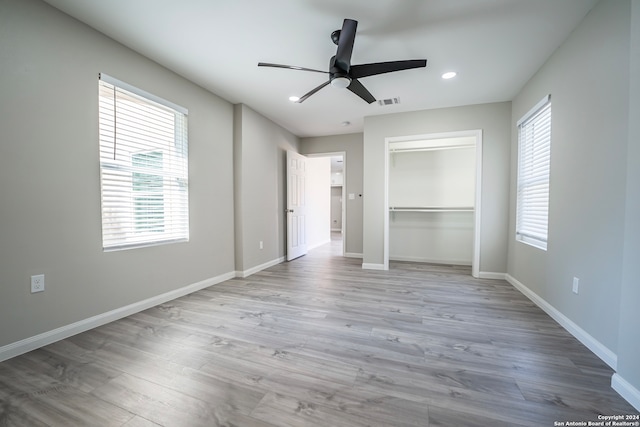 unfurnished bedroom featuring ceiling fan, light hardwood / wood-style flooring, a closet, and a spacious closet