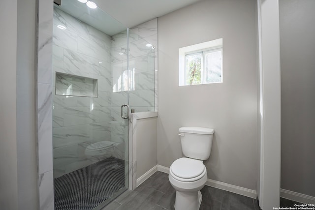 bathroom featuring hardwood / wood-style flooring, a shower with door, and toilet