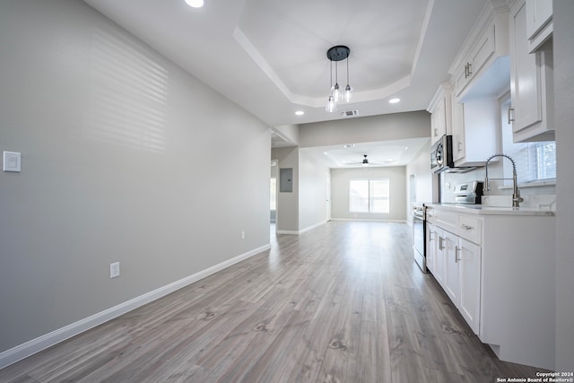 kitchen featuring a tray ceiling, light hardwood / wood-style flooring, sink, stainless steel appliances, and white cabinetry