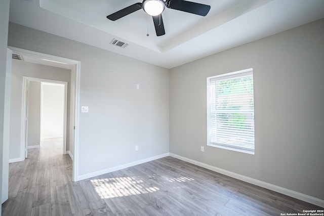 spare room with ceiling fan, hardwood / wood-style flooring, and a tray ceiling