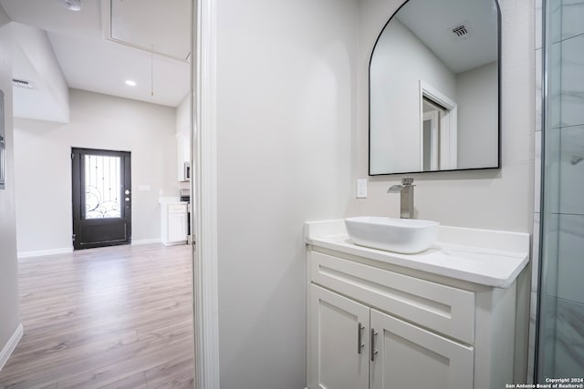 bathroom featuring wood-type flooring, a shower with shower door, and vanity