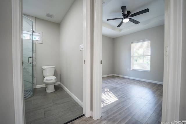 bathroom with hardwood / wood-style floors, an enclosed shower, ceiling fan, and toilet