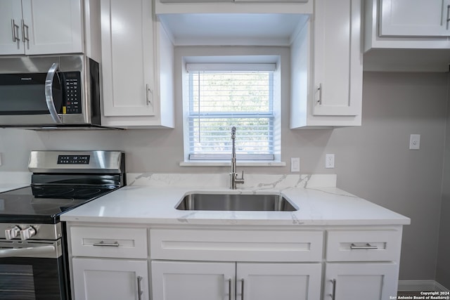 kitchen featuring light stone counters, sink, stainless steel appliances, and white cabinets