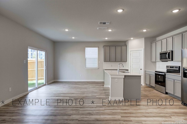 kitchen with a center island with sink, appliances with stainless steel finishes, and gray cabinetry