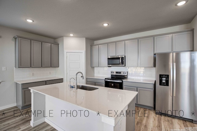 kitchen with light hardwood / wood-style floors, a kitchen island with sink, gray cabinetry, sink, and stainless steel appliances