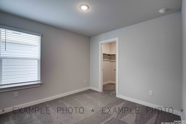 unfurnished bedroom with a spacious closet, carpet floors, and a closet