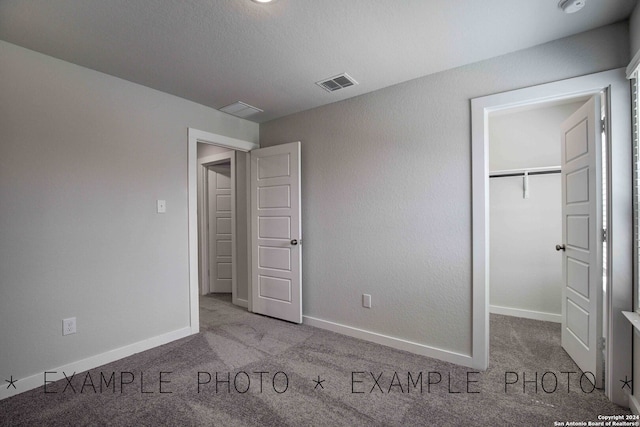 unfurnished bedroom featuring light carpet, a closet, and a spacious closet