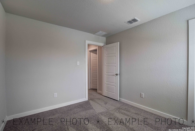 carpeted spare room with a textured ceiling