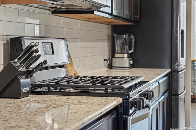 kitchen featuring stainless steel range with gas cooktop, light stone counters, and tasteful backsplash