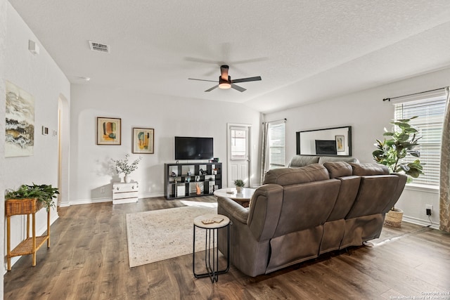 living room with ceiling fan, vaulted ceiling, dark hardwood / wood-style floors, and a textured ceiling