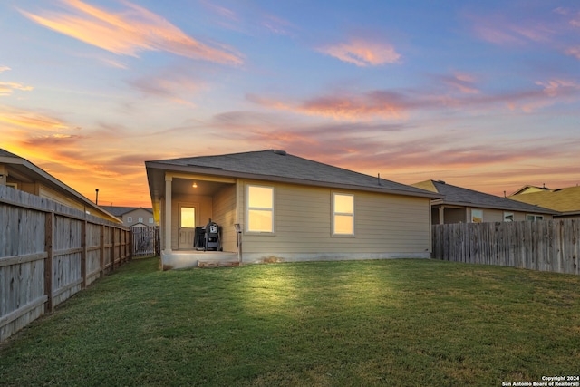 back house at dusk with a yard and a patio area