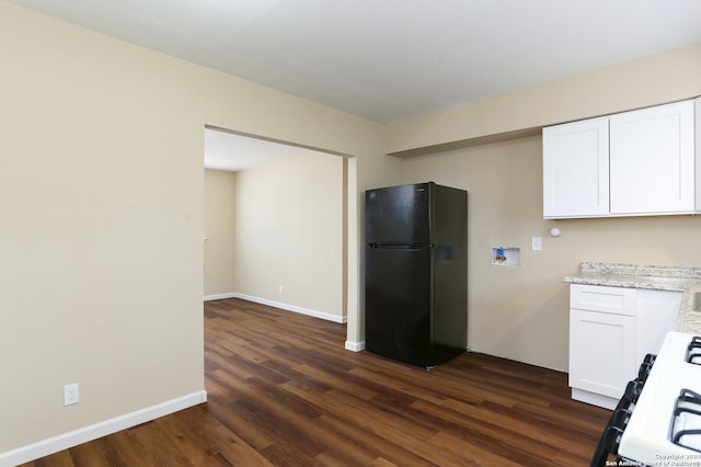 kitchen featuring stove, dark hardwood / wood-style flooring, black fridge, light stone countertops, and white cabinetry