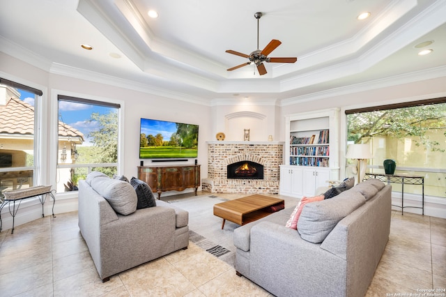 tiled living room with a tray ceiling, crown molding, a fireplace, and a healthy amount of sunlight