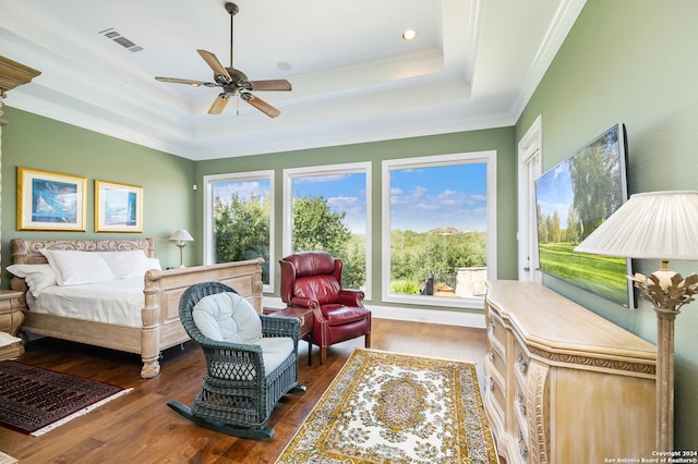 bedroom with ceiling fan, ornamental molding, a tray ceiling, and dark wood-type flooring