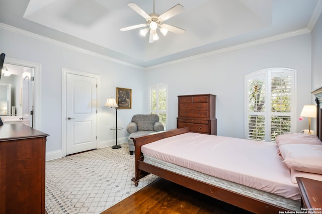 bedroom featuring ceiling fan, light hardwood / wood-style floors, ornamental molding, and a tray ceiling