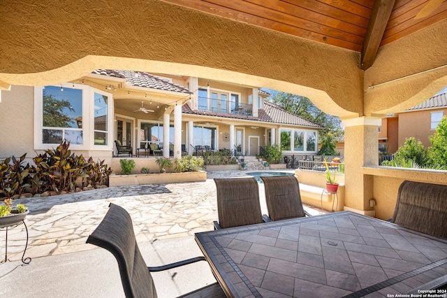 view of patio with ceiling fan, a balcony, and a hot tub