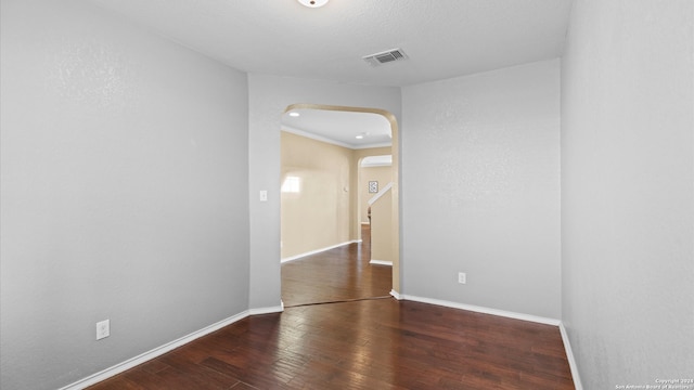 empty room with an AC wall unit, crown molding, and dark hardwood / wood-style floors