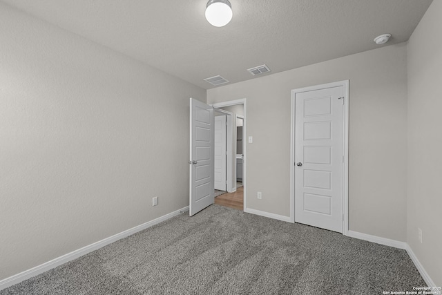 unfurnished bedroom with carpet floors, a textured ceiling, and a closet