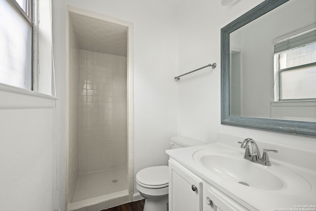 bathroom featuring vanity, hardwood / wood-style floors, toilet, and tiled shower