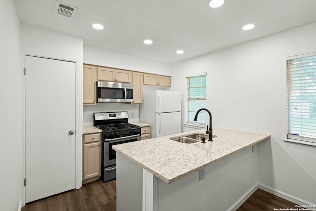 kitchen featuring dark wood-type flooring, sink, light stone counters, appliances with stainless steel finishes, and a kitchen bar