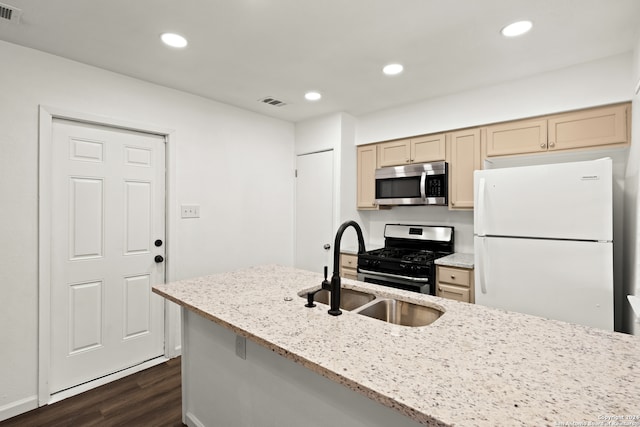 kitchen with light stone counters, sink, cream cabinets, stainless steel appliances, and dark hardwood / wood-style flooring