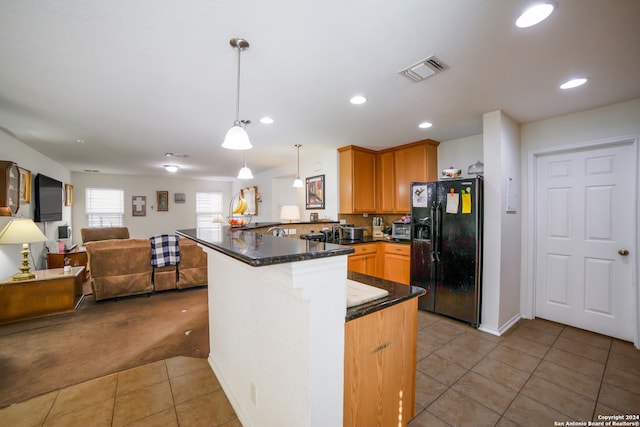 kitchen featuring light tile patterned flooring, kitchen peninsula, hanging light fixtures, and black fridge