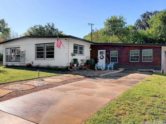 ranch-style house with a front lawn and a patio