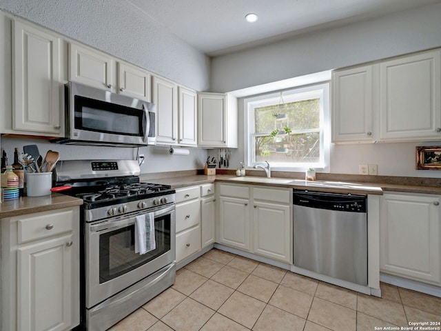 kitchen featuring light tile patterned flooring, stainless steel appliances, sink, and white cabinetry