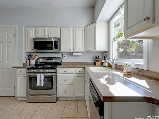 kitchen featuring light tile patterned floors, stainless steel appliances, sink, and white cabinetry