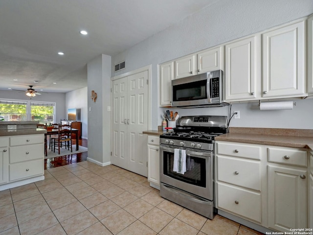 kitchen with ceiling fan, light tile patterned flooring, stainless steel appliances, and white cabinetry