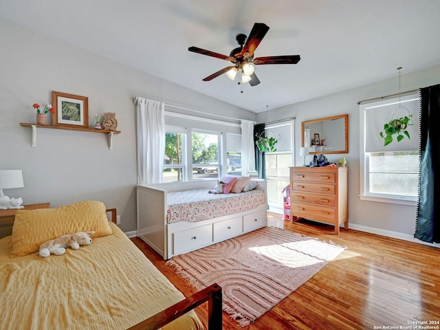 bedroom with light wood-type flooring, multiple windows, ceiling fan, and vaulted ceiling