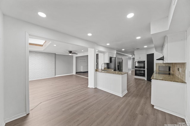 kitchen featuring white cabinetry, stainless steel refrigerator with ice dispenser, light hardwood / wood-style floors, kitchen peninsula, and dark stone counters