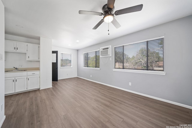 kitchen featuring light hardwood / wood-style floors, sink, a wall unit AC, and white cabinets