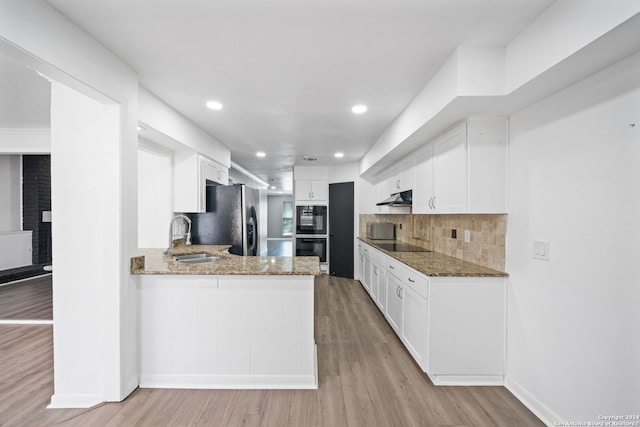 kitchen featuring stone counters, kitchen peninsula, white cabinetry, sink, and black appliances