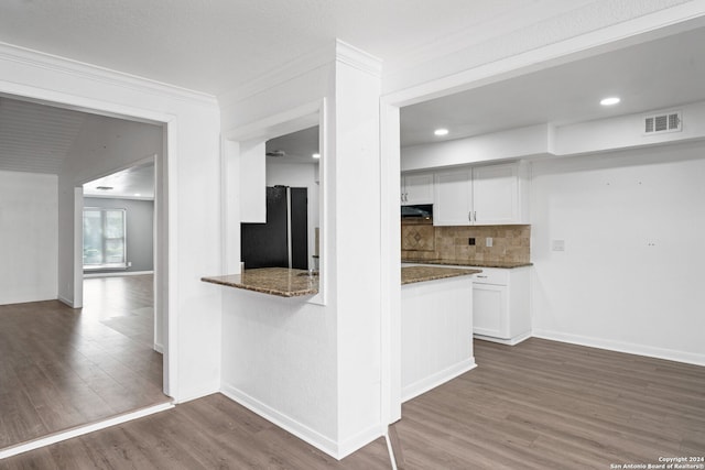 kitchen featuring black fridge, white cabinetry, dark stone countertops, dark hardwood / wood-style floors, and backsplash